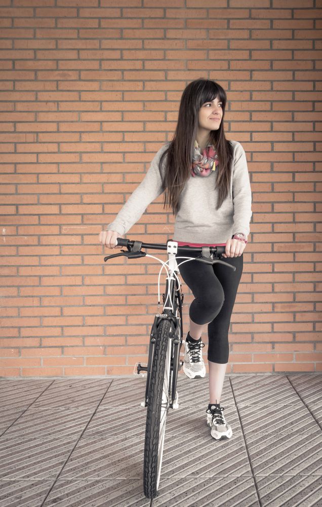 Sportive woman with fixie bike over a brick wall