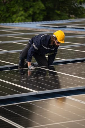 Engineer worker using electric drill repairing on solar cell panel on the roof of the factory. After service and security for industrial renewable energy concept