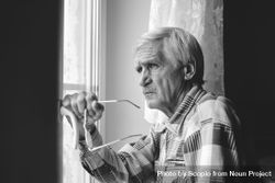 Grayscale photo of older man looking outside the window 56dDVb