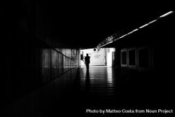 Silhouette of person walking through underground tunnel 0W7Lx0
