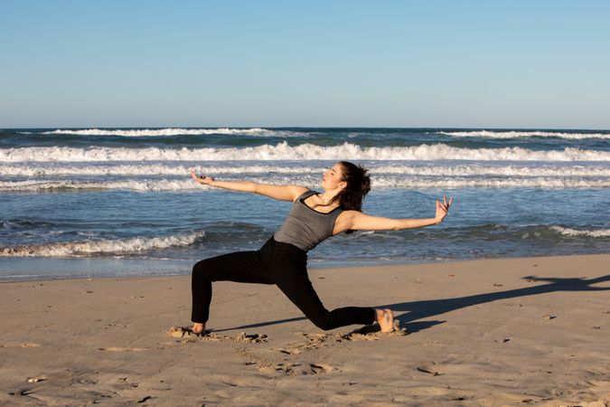 Young woman dancing and posing near water on shore