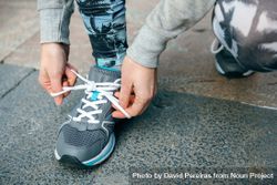 Close up of female runner tying her sneakers laces to training 0KMyEN