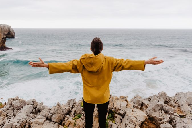 Person in yellow hoodie on stony shore