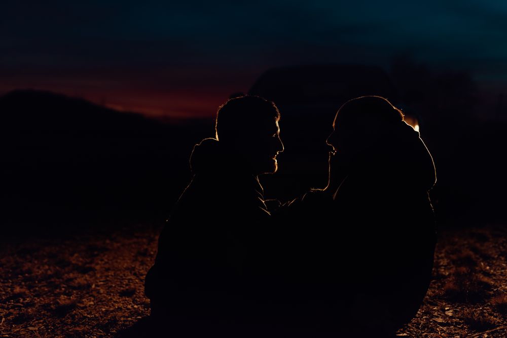 Men hugging and sitting on ground on field at night