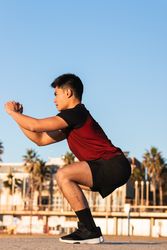 Asian sporty man doing lunges in the beach