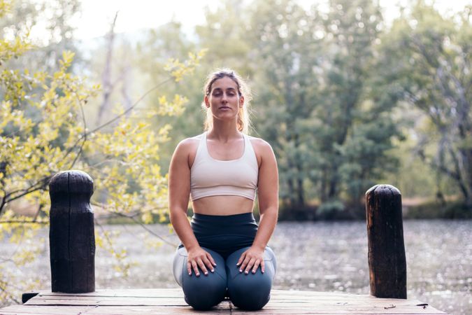 Woman meditating in nature near a lake