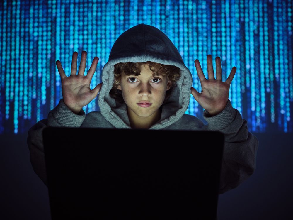 Programmer boy with hands up at laptop
