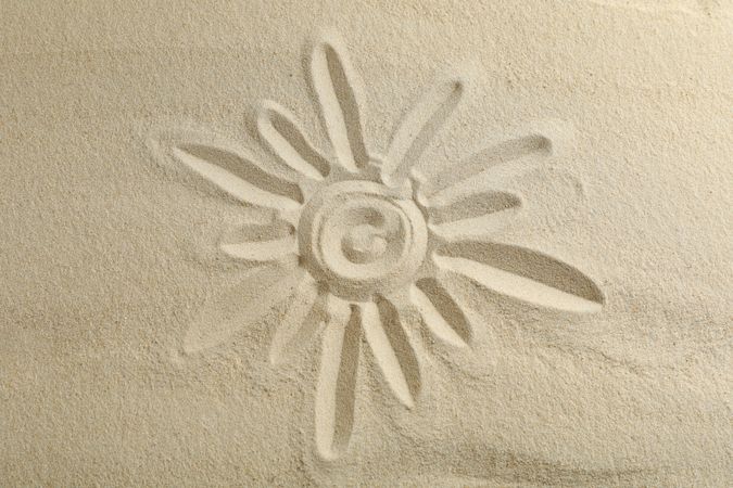 Sun drawing on clear sea sand, space for text and top view. Summer vacation background