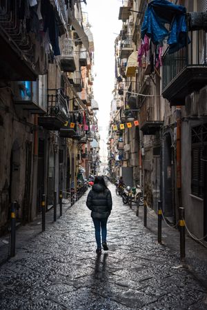 Anonymous female traveler in warm wear walking on narrow old street