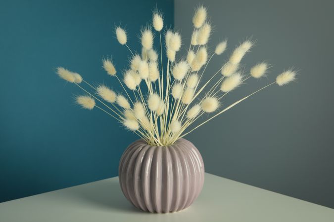Round and ridged vase in blue and grey room filled with dried flowers