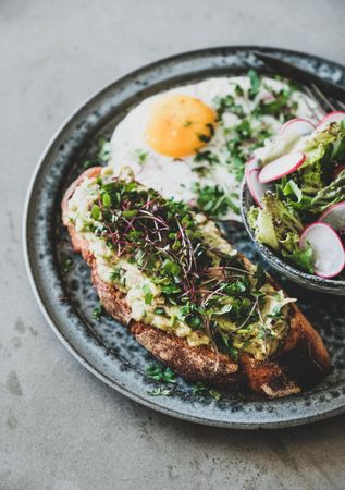 Avocado toast on sourdough bread with herbs and sprouts, selective focus