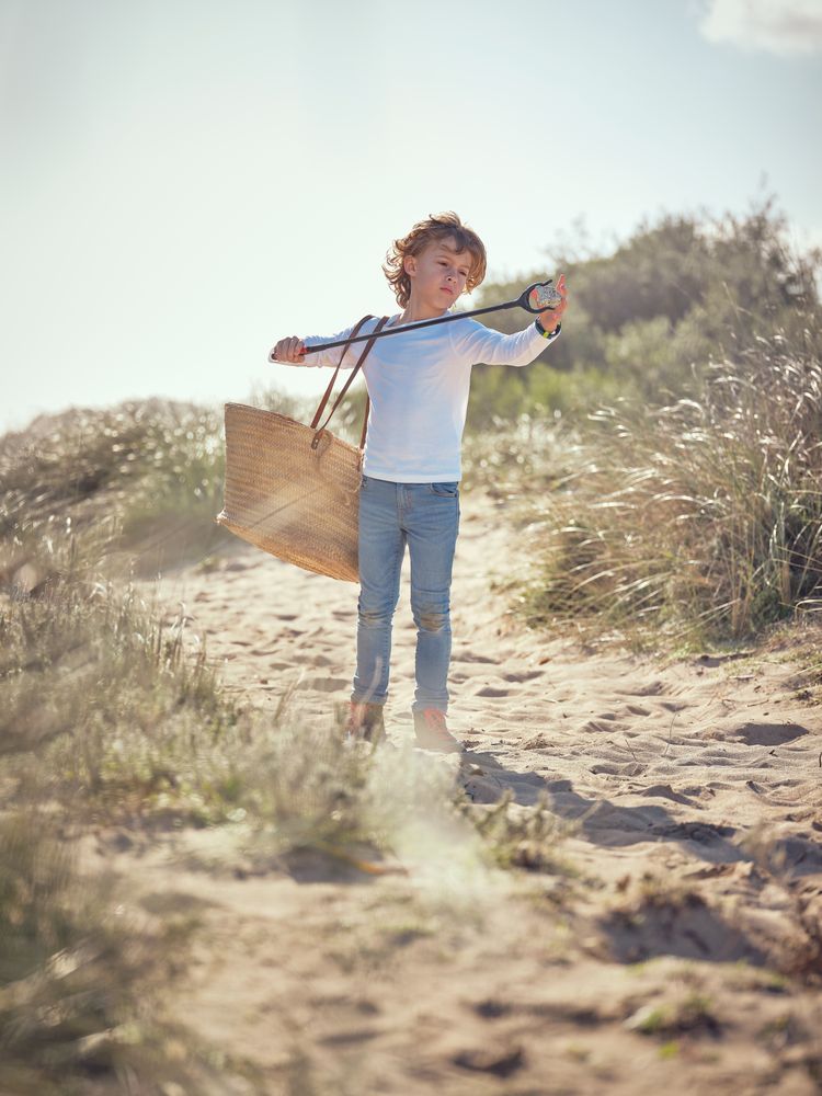 Adorable preteen boy picking up garbage with trash grabber