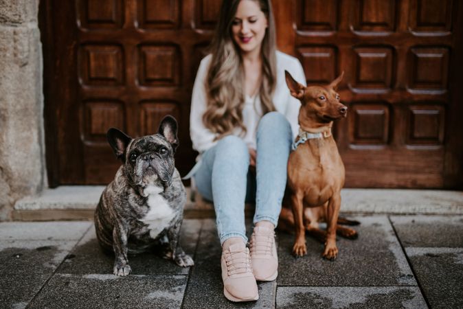 Stylish woman with dogs sitting on street