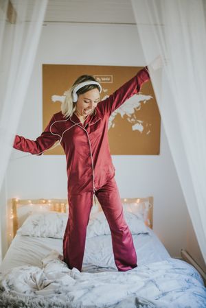 Woman with headphones dancing in bed