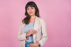 woman wearing a pink breast cancer awareness ribbon while showing it.