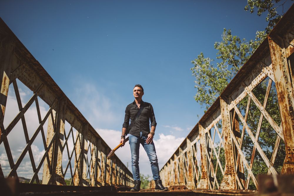 Man with guitar standing on bridge