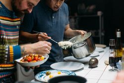 Two friends serving risotto with parmigiano reggiano