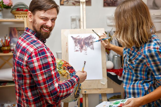 A man and woman draw an abstract painting with oil paints