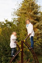 Two fun young girls climbing playground stairs in park