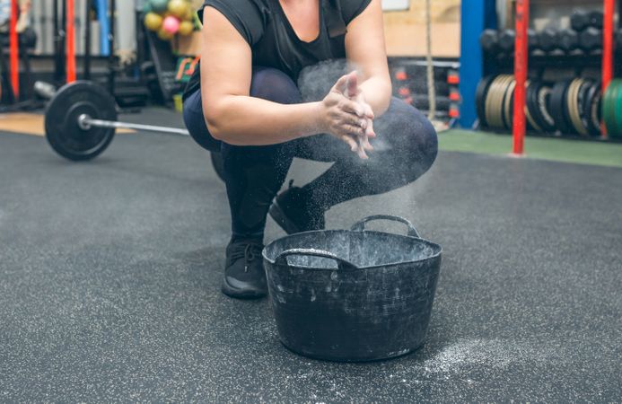 Unrecognizable woman applying magnesium to practice weightlifting