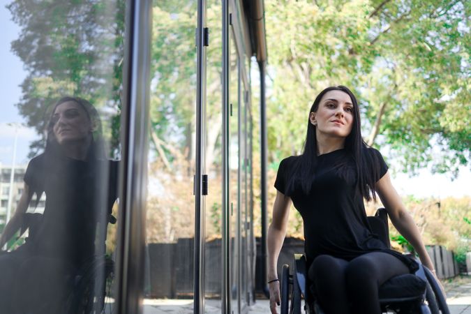 woman in wheelchair outside next to window