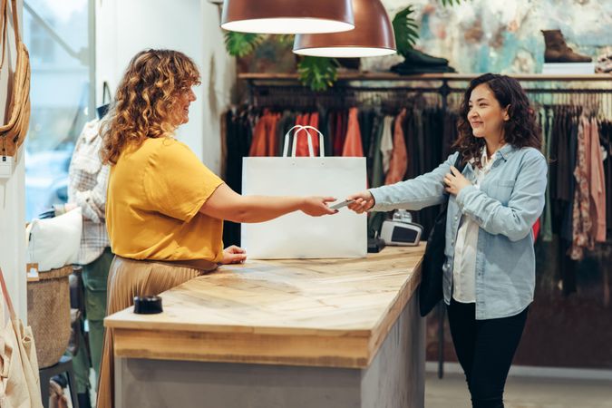 Female customer paying for purchase with credit card at clothing store