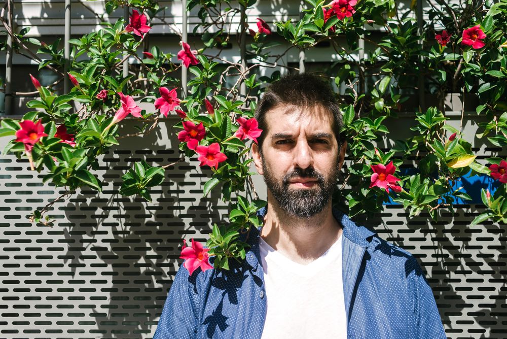 Man standing outside in front of floral wall