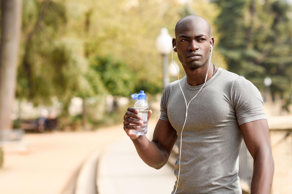 Fit male drinking from a water bottle in an outdoor park