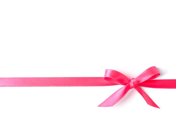 Pink ribbon with bow isolated on plain background. Gift concept