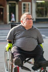 Portrait of man sitting in wheelchair in city street