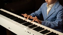 Side view of young boy playing digital piano