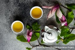 Top view of magnolia flowers with green tea and teapot on grey background 5ngOQm