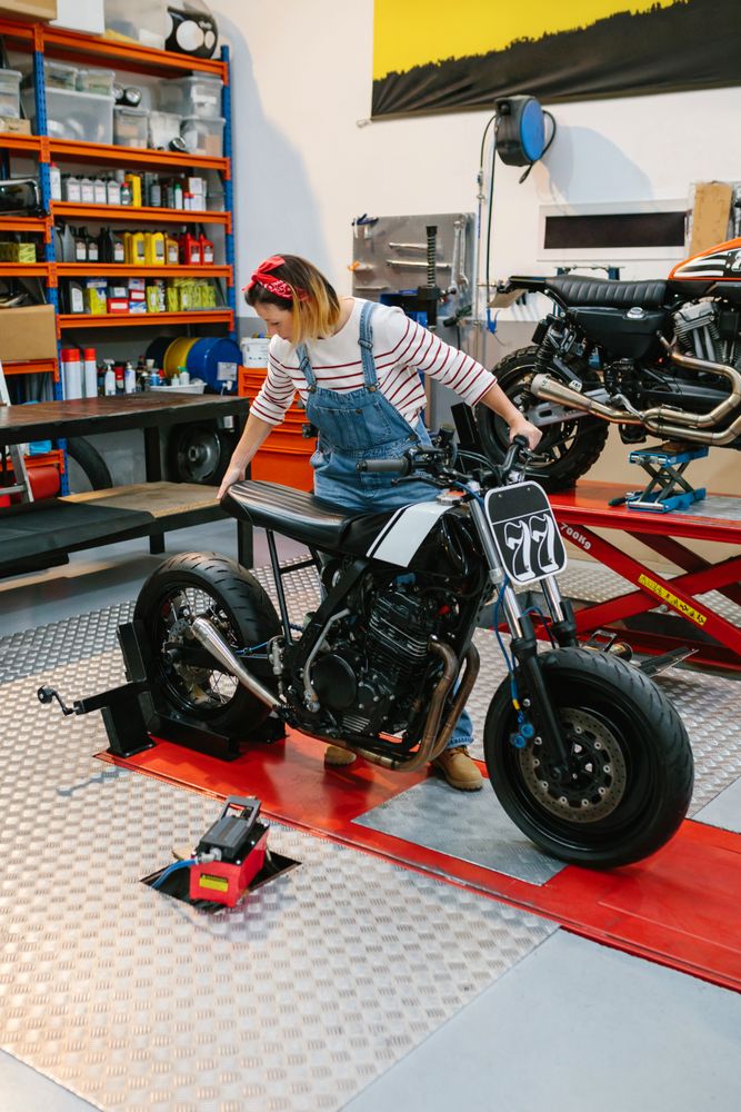 Mechanic woman placing custom motorcycle over platform
