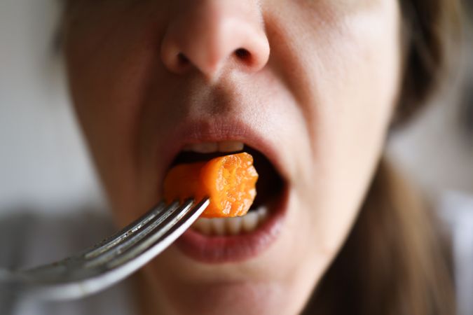 Detail of a woman eating a nutritional and healthy carrot.