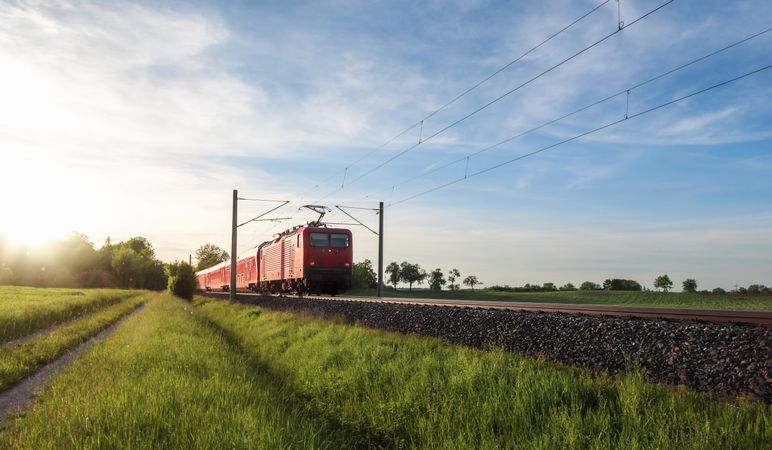 Red train traveling in a summer landscape