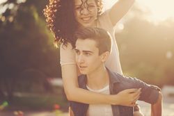 Teenage girl on her boyfriend’s back in piggy back outside