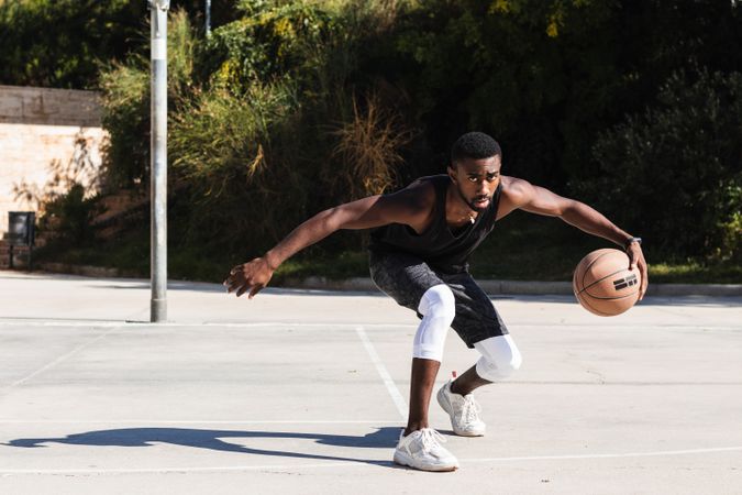 Black man playing basketball on sports ground