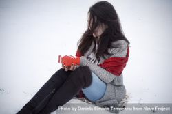 Woman holding gift and sitting on snow 41OoL0