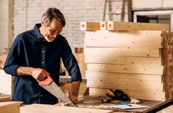 Man sawing wooden plank