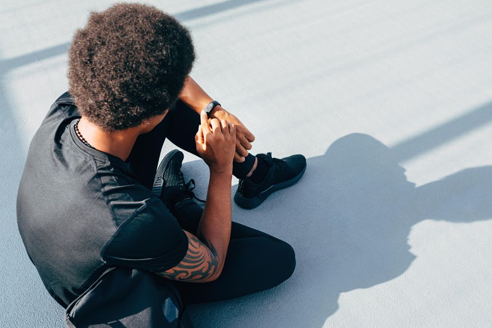 Young man sitting on the ground looking at watch