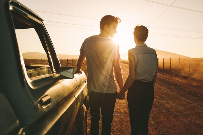 Young male and female holding hands while sun is setting
