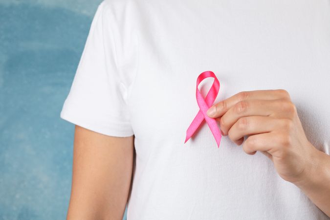 Person in t-shirt hold awareness ribbon against blue background