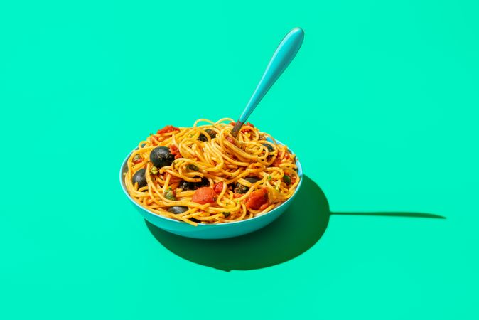 Spaghetti puttanesca bowl isolated on a green background
