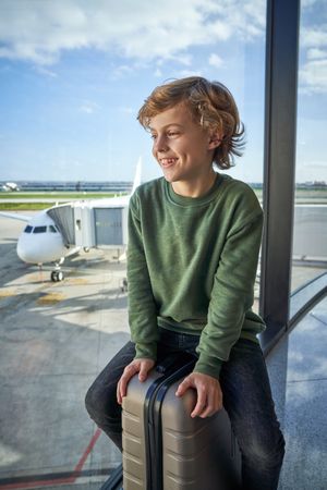 Cute boy sitting on suitcase