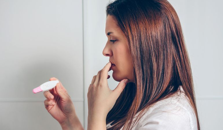 Pregnant looking at a pregnancy test