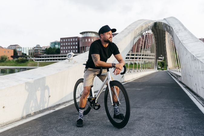 Cheerful man with bicycle standing on footbridge