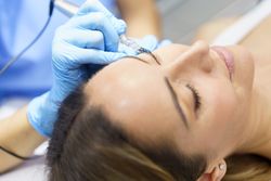 Woman having eye lashed put on in salon