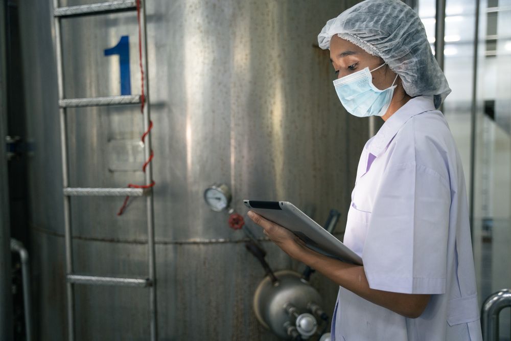 A food factory researcher inspecting canned food conveyor belt machine.