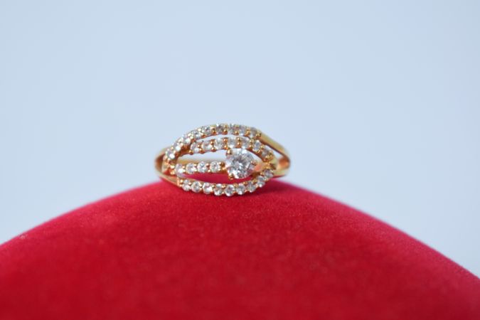 Woman's diamond ring resting on red cushion