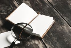 Open notebook and magnifying glass on wooden table